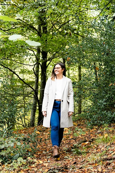 Martha Wood walking through a quiet Cumbrian forest, enclosed by trees on all sides